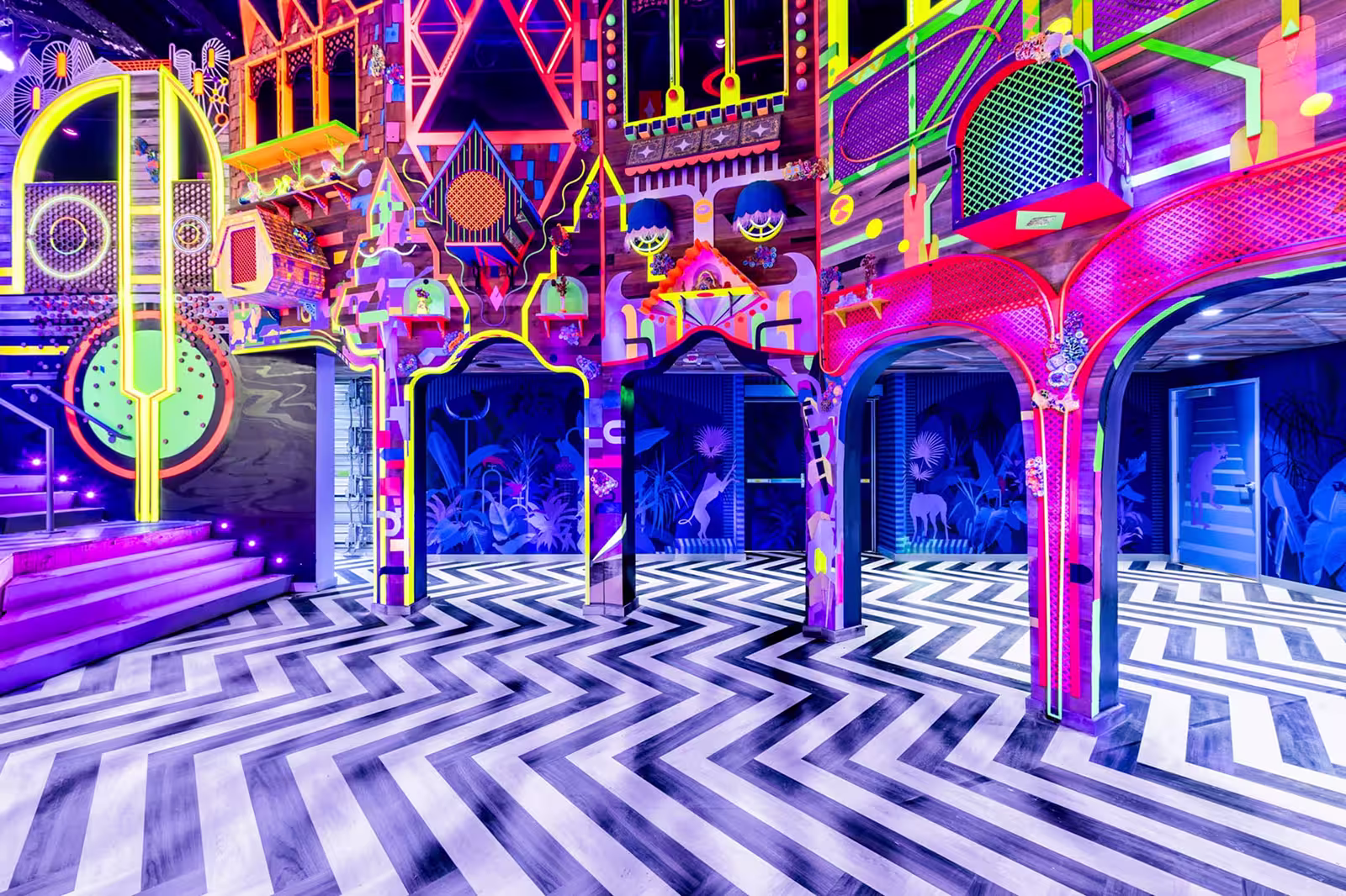 room with neon colors and black and white striped floor at Meow Wolf Grapevine