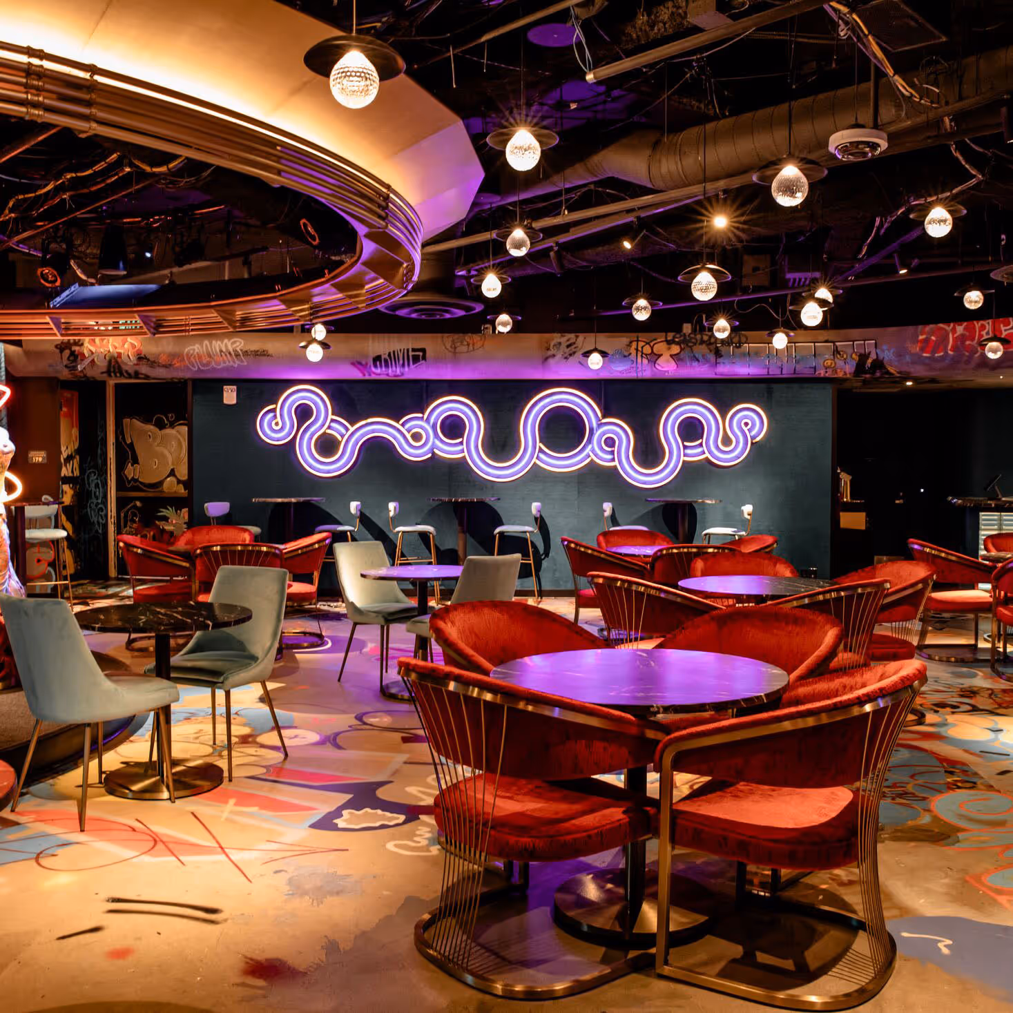 Guests sharing neon drinks at Meow Wolf Denver’s Convergence Station lounge. Immersive art bar & cafe experience in Colorado.